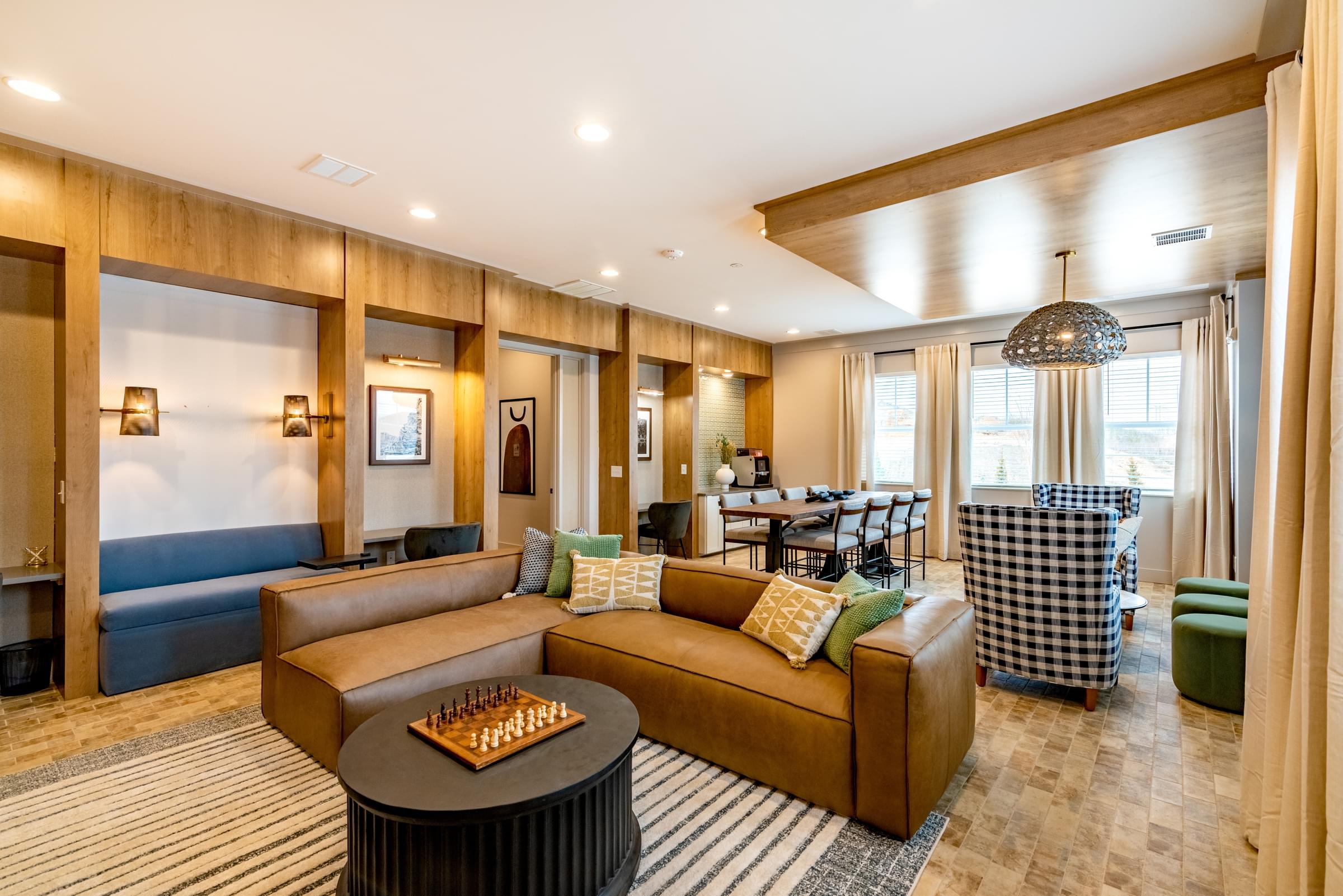 A living room with a brown couch and a chess board on the coffee table
