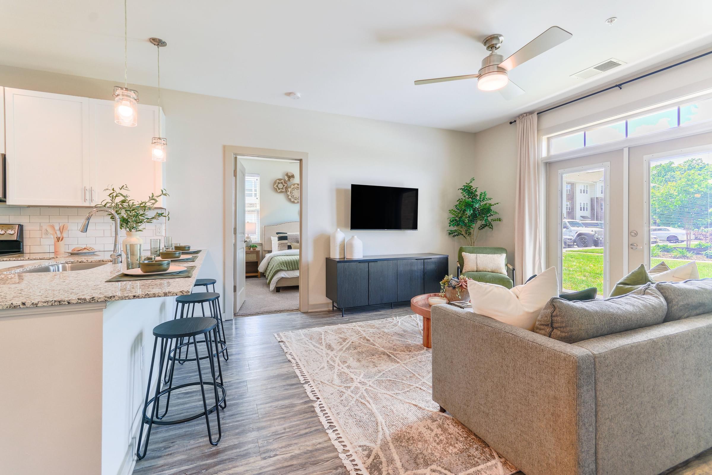 a living room with a couch and a kitchen with a bar and a tv