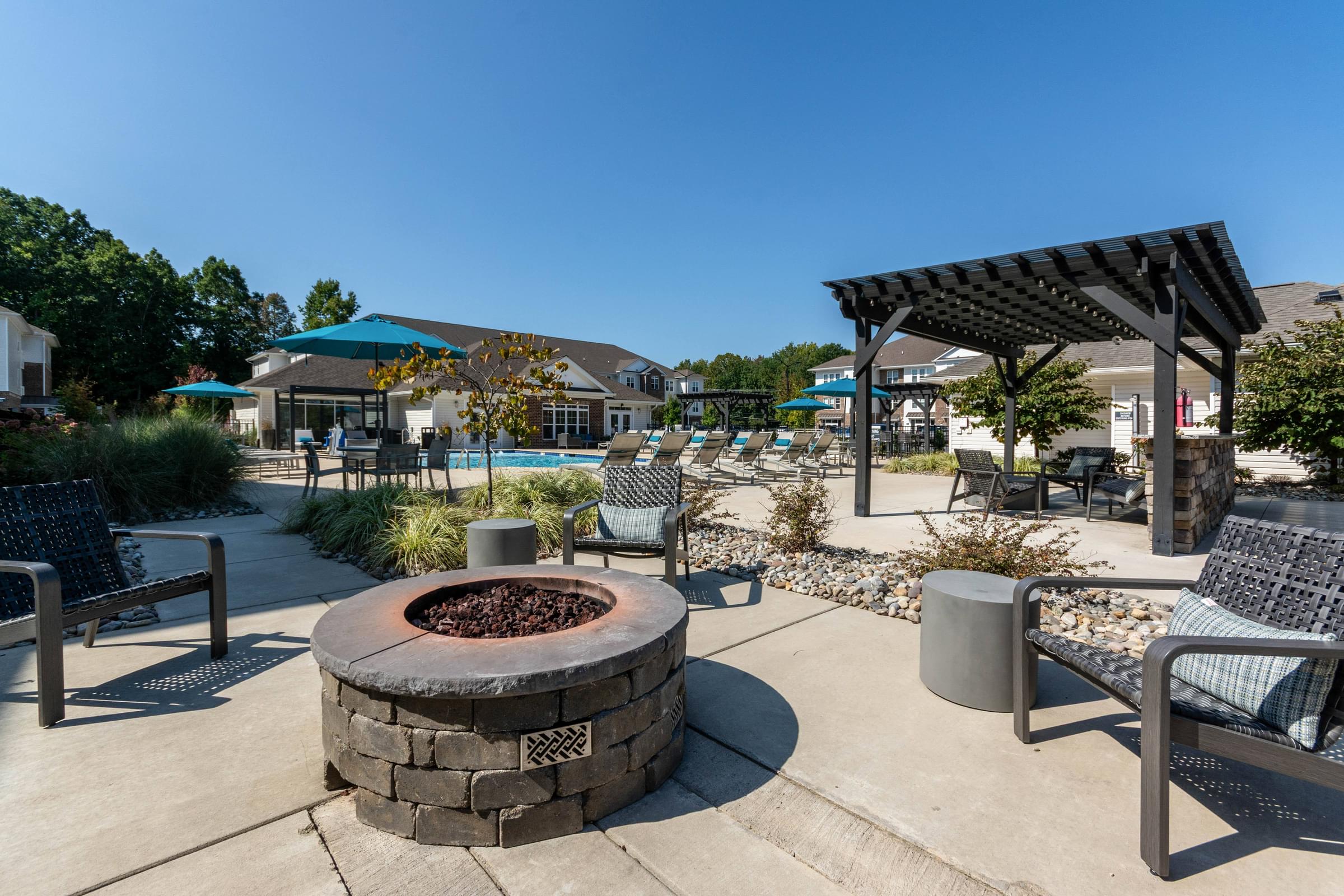 A fire pit sits in the middle of a patio with chairs and a table nearby at Hawthorne St. Marks in Burlington, NC.