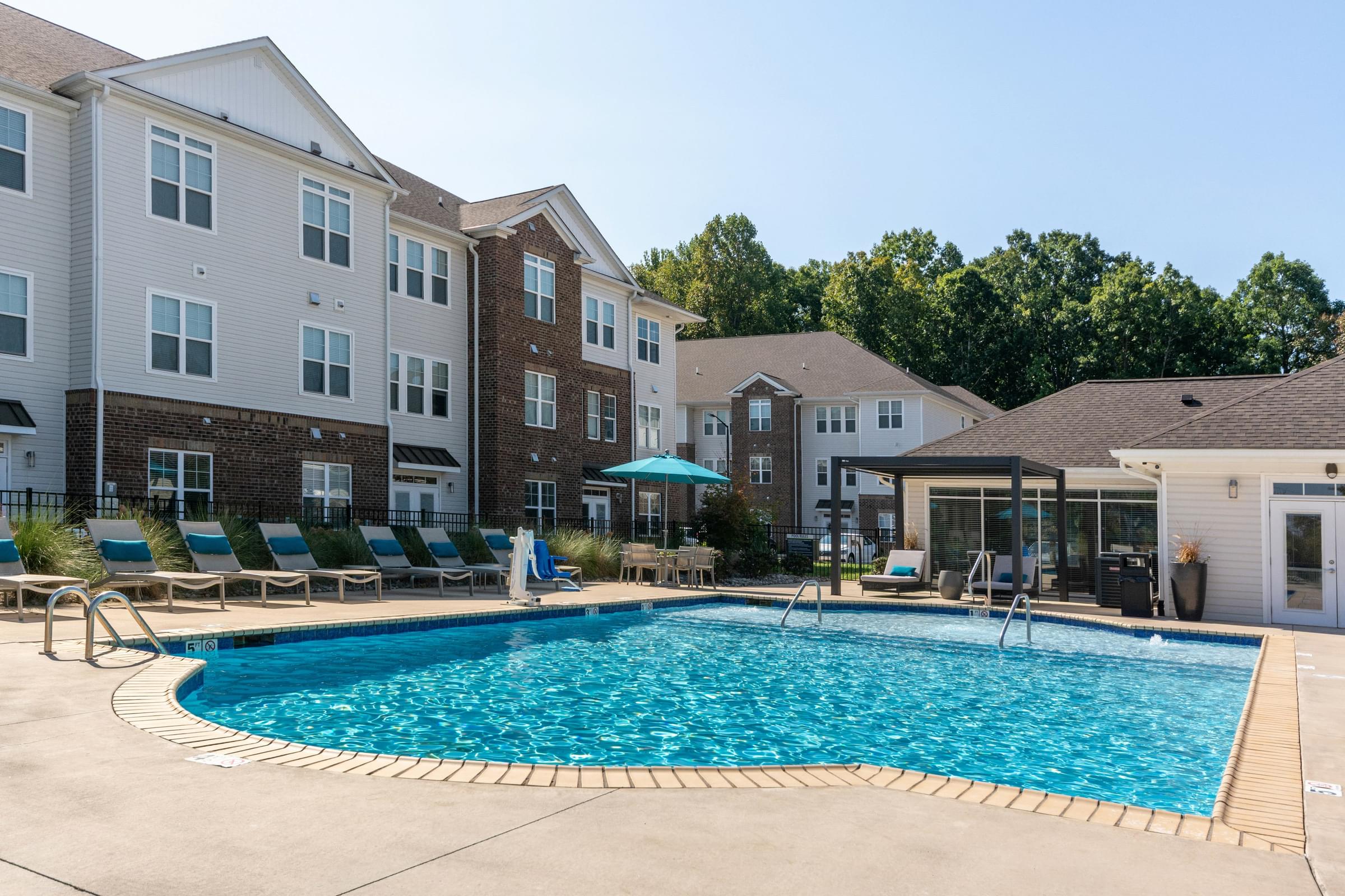 A swimming pool in front of apartment buildings at Hawthorne St Marks in Burlington, NC