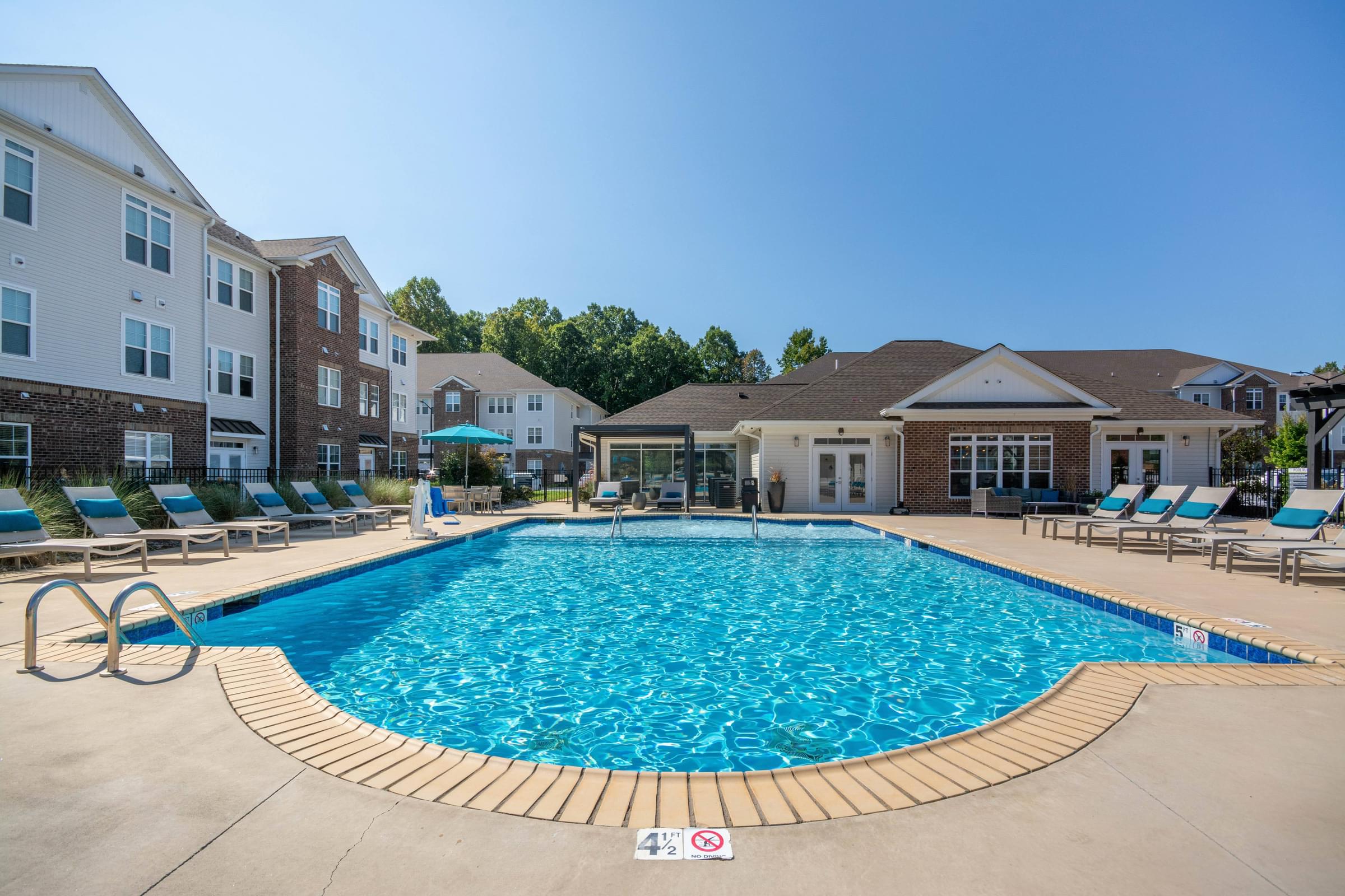 A large swimming pool surrounded by lounge chairs and buildings in the background at Hawthorne St Marks in Burlington, NC