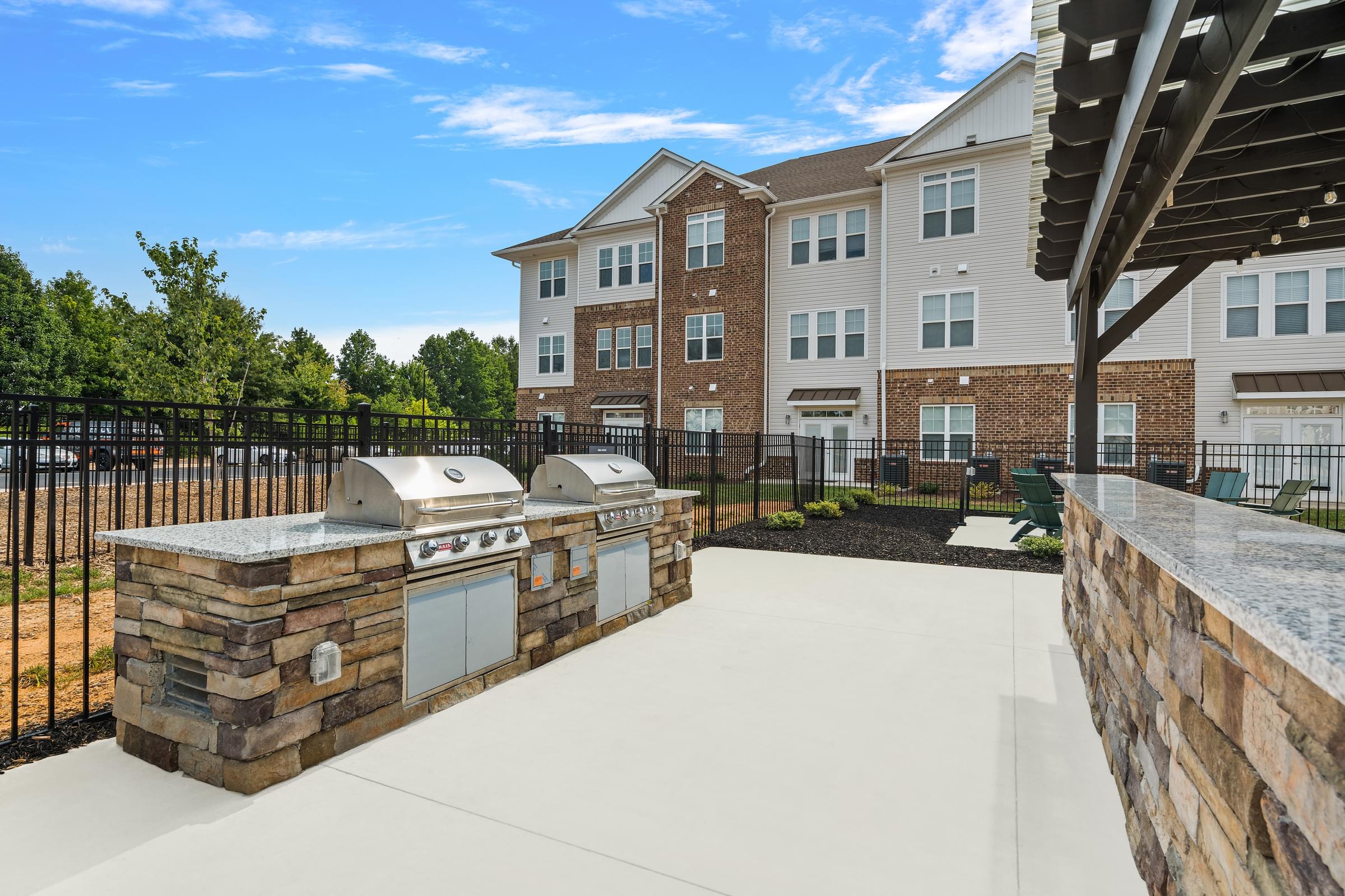 an outdoor kitchen with two bbq grills in front of an apartment building