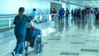 Carer Pushing Elderly Man Through an Airport