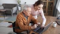 Elderly Man and Young Woman Using a Laptop