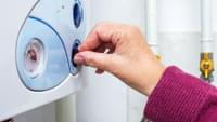 Elderly Woman Turning on a Boiler