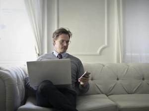 Man Using Phone and Laptop