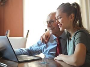 Old Man and Young Woman Using Laptop