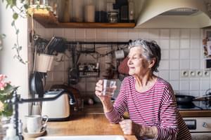An elderly woman standing in the kitchen holding 2022 02 02 03 48 47 utc 1