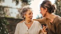 Daughter greeting senior mother in garden