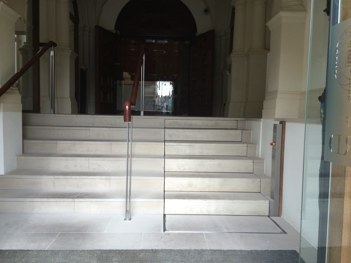 White marble clad staircase with a Sesame hidden wheelchair lift on the right hand side