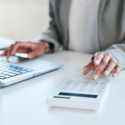 Person types on their laptop and uses a calculator