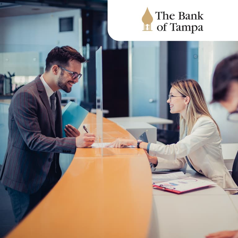 Bank professional (right) speaks with a customer (left) across a counter