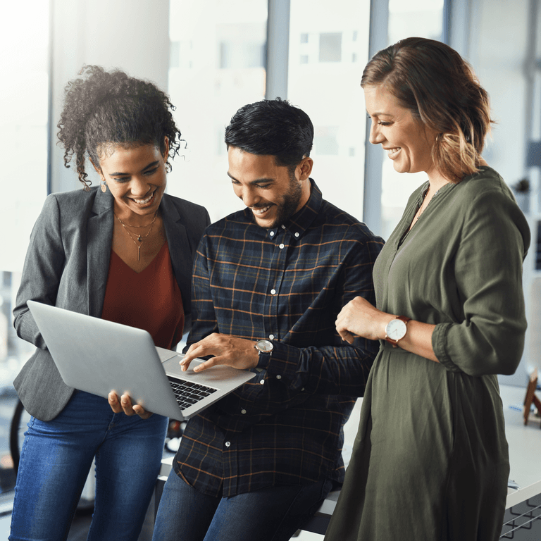 Three smiling colleagues looking at a laptop