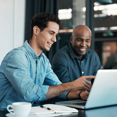 Two accounts receivable professionals sit reviewing what's on a laptop