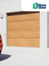 Rear end of red car parked beside a wooden garage door against a concrete garage