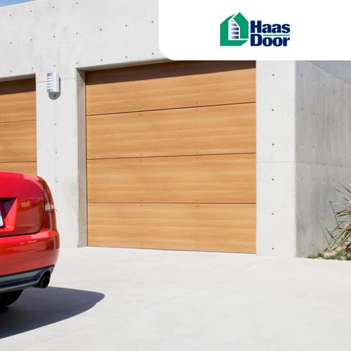 Rear end of red car parked beside a wooden garage door against a concrete garage