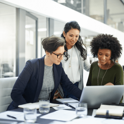 Three people surround a laptop on a table