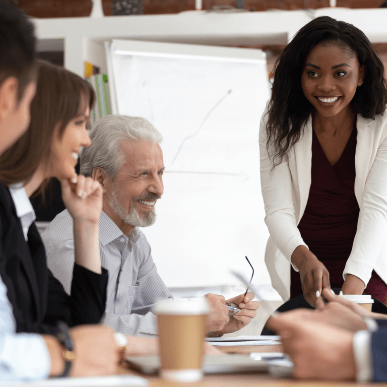 Smiling colleagues surround a table, talking about finance transformation