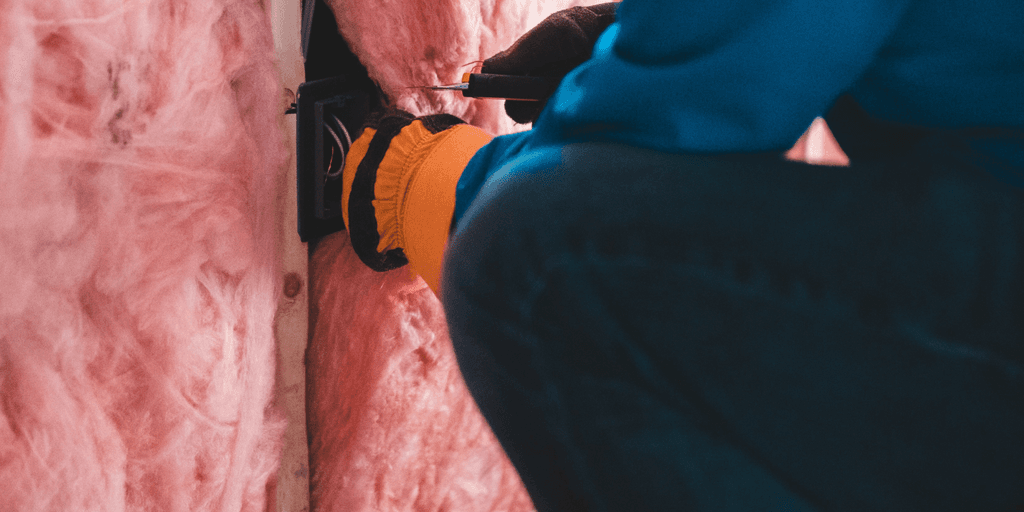 Person kneels while installing insulation