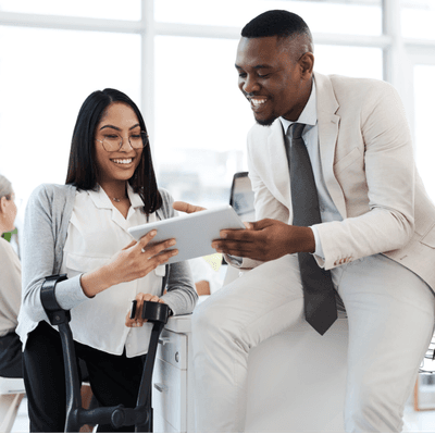 Two colleagues are smiling, facing a tablet they're both holding