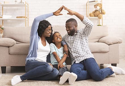 Hintergrundbild Versicherungsunternehmen zeigt eine fröhliche Familie im Wohnzimmer