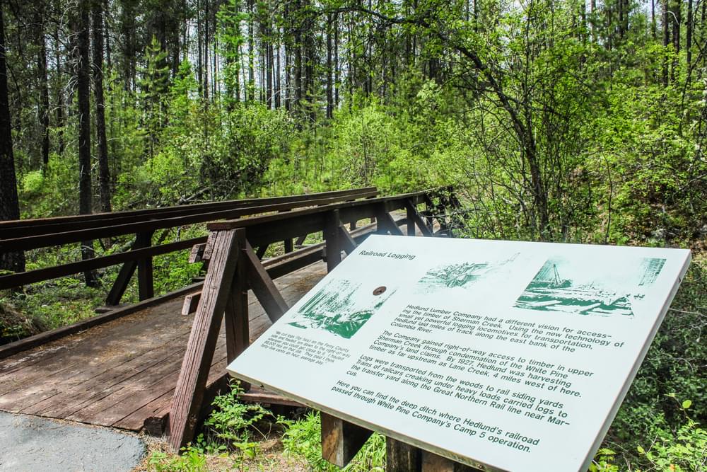 A view of the a trestle bridge over the accessible Log Flume Trail, with interpretive signage.