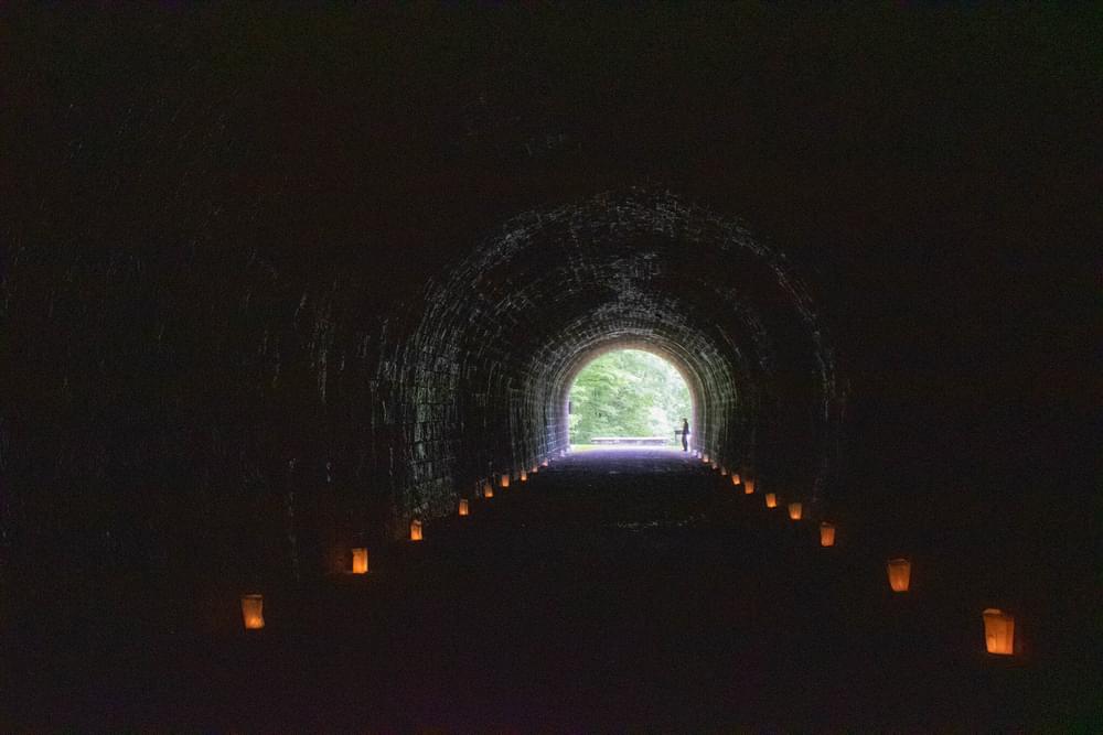 A National Park Service Ranger stands outside the Staple Bend Tunnel, the first railroad tunnel in the United States, waiting for runners of the 8th annual Path of the Flood Historic Races to pass through. Luminaries are lit in memory of those that lost their lives during the 1889 Johnstown Flood, the race takes place the anniversary weekend of this every year.