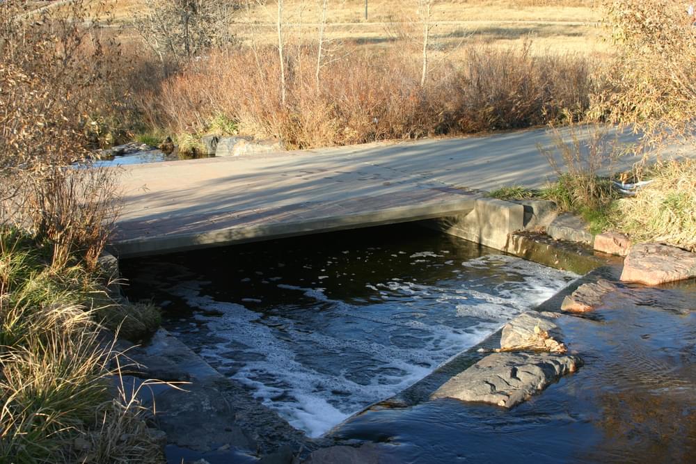 Concrete structure carries trail over a small stream at Bible Park in Denver, Colorado