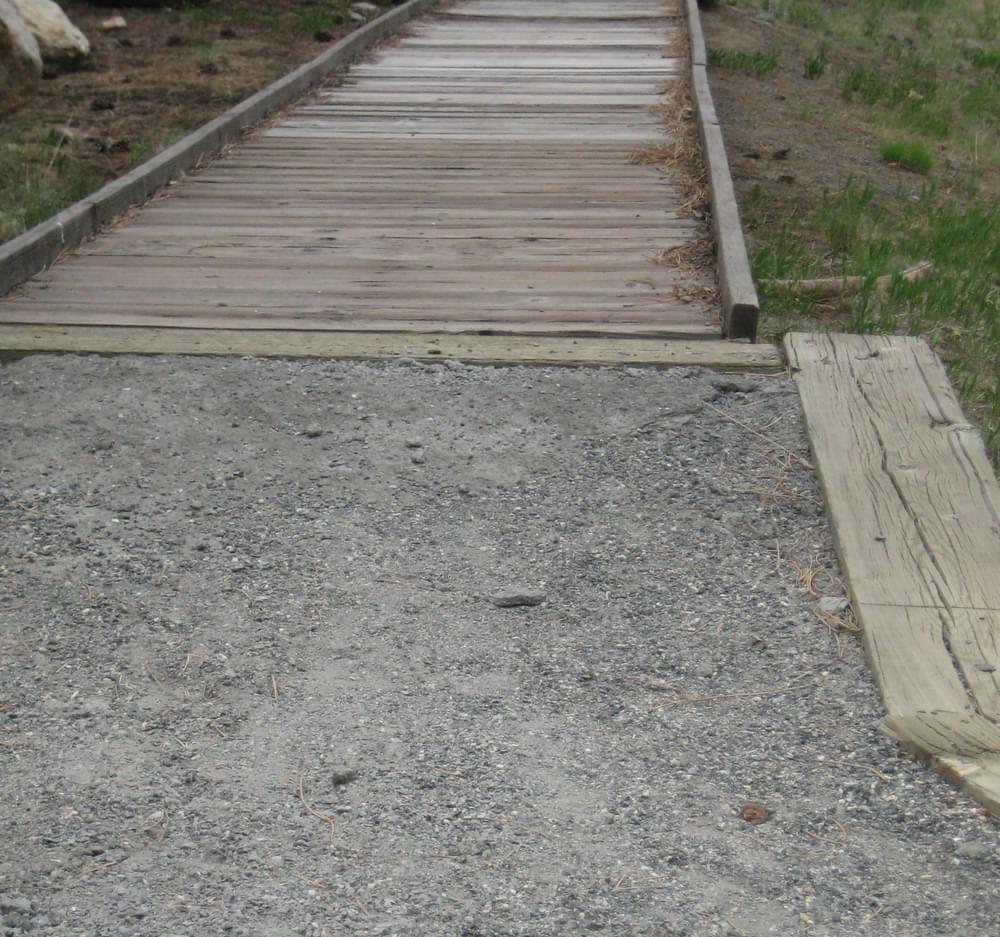 A heavy timber extends along the bridge approach to retain the trail surfacing material (crushed stone); Easter Seals Handicamp, Empire, Colorado