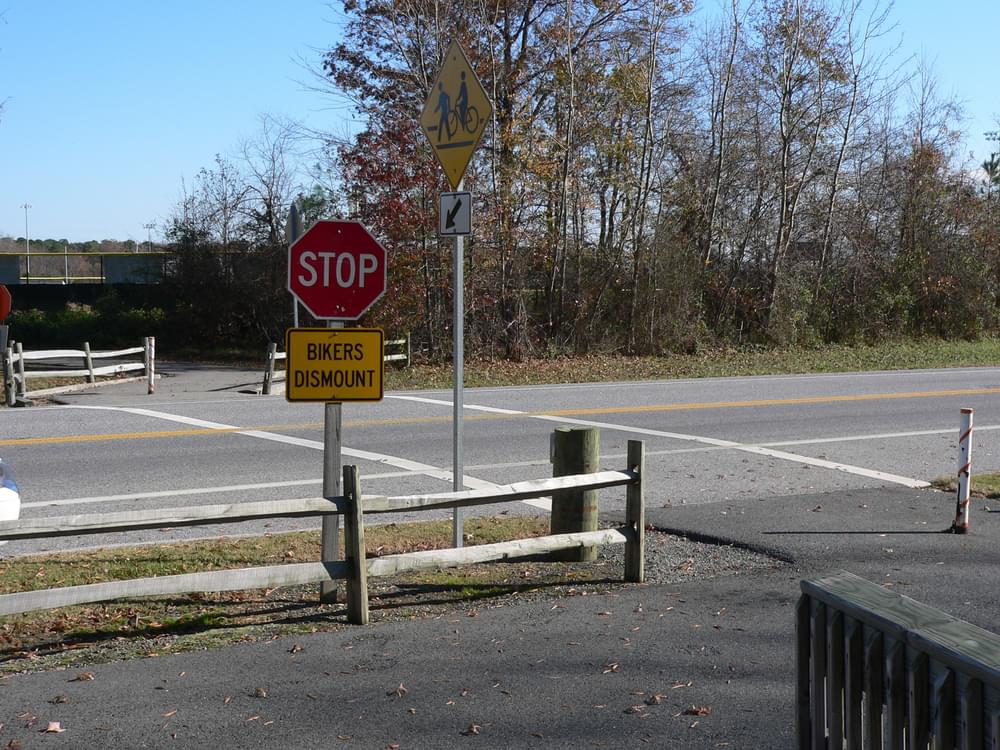 All the elements of a road/trail crossing: Stop sign and warning sign for trail users; ped/bike crossing warning for motorists; crosswalk painted on roadway; and fencing to force trail users to slow at the road