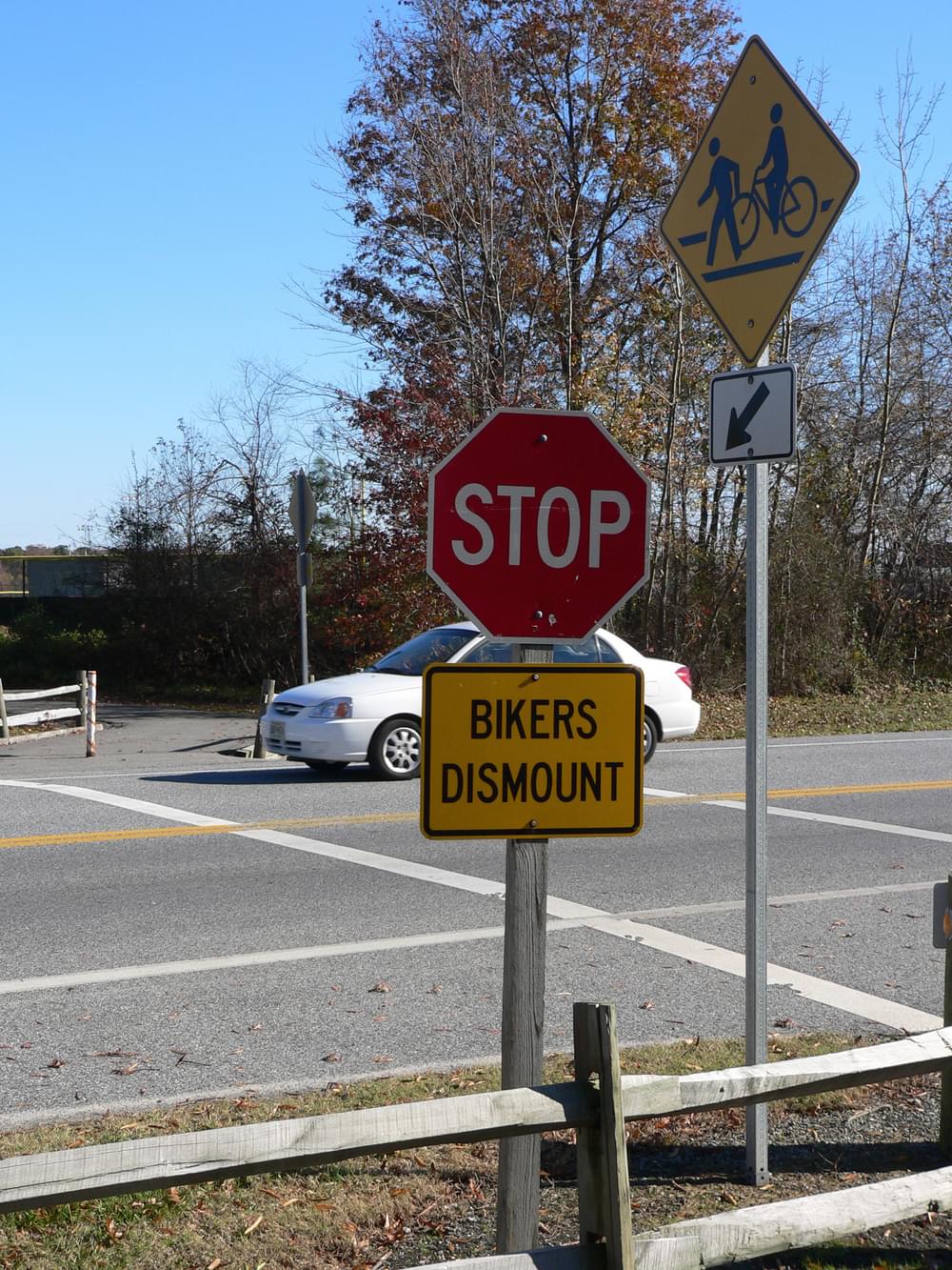 In addition to stop sign for trail users, motorists see yellow highway warning sign with bike/ped symbols; on the Eastern Shore of Maryland