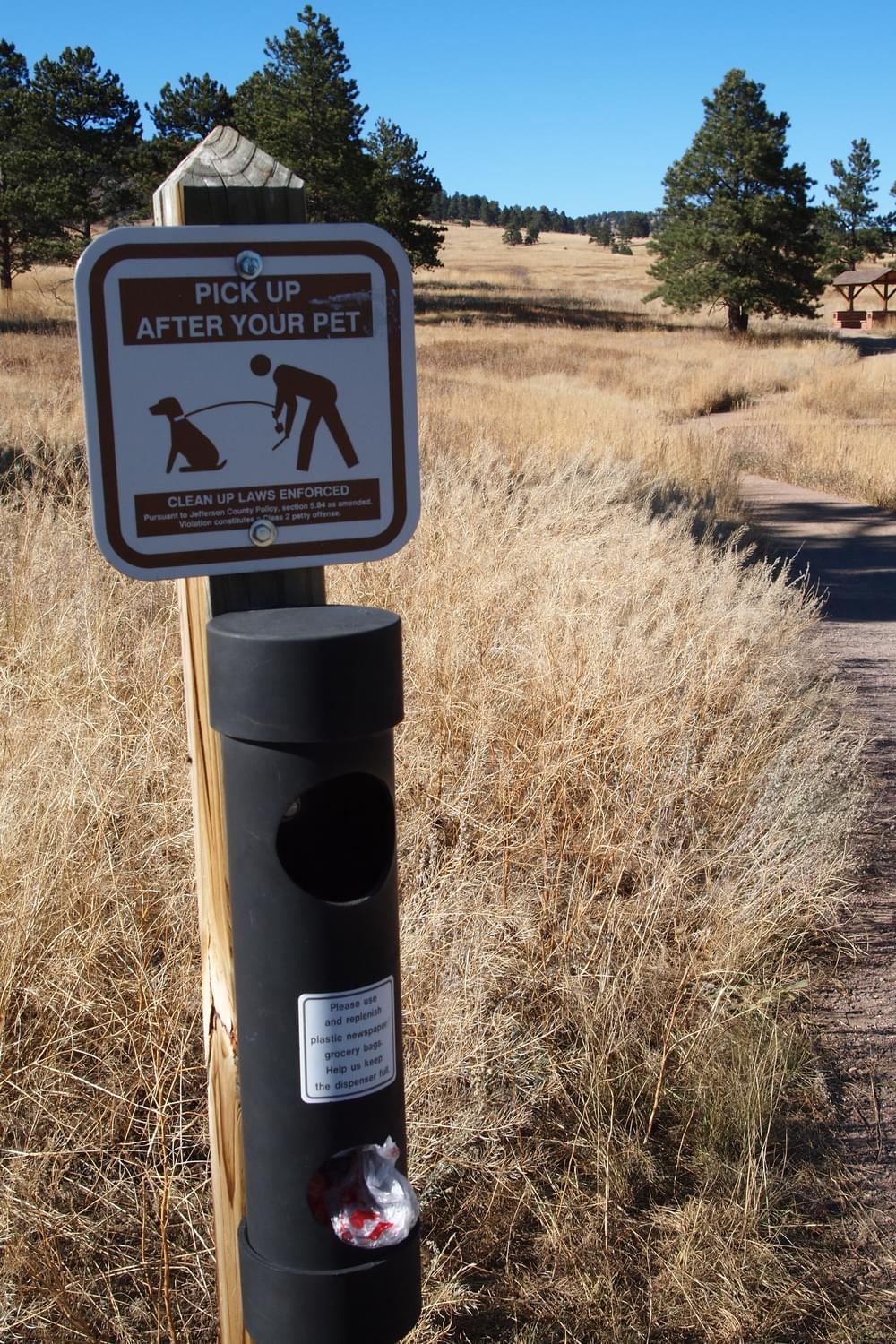 Sign and dog waste bag dispenser in Elk Meadow Park; Jefferson County Open Space, Colorado