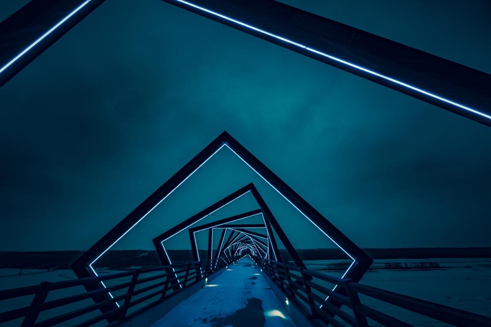 Modern geometric neon bridge architecture at night on walkway; High Trestle Trail Bridge, Madrid, Iowa