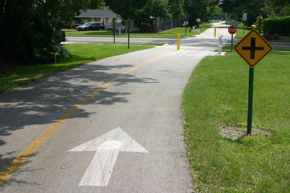 Trail users are warned by a standard highway crossroads sign with painted arrow to guide them to right lane; Orlando, Florida, Cady Way Trail