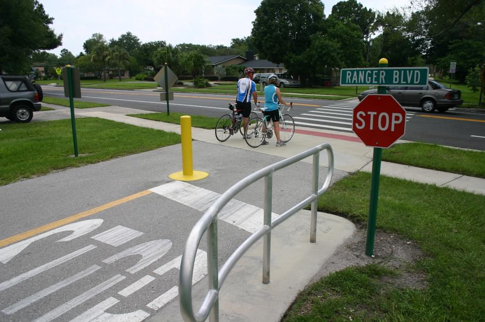 Highly developed crossing with stop sign, symbolic bollard, and mysterious handrail on Orlando's Cady Way Trail