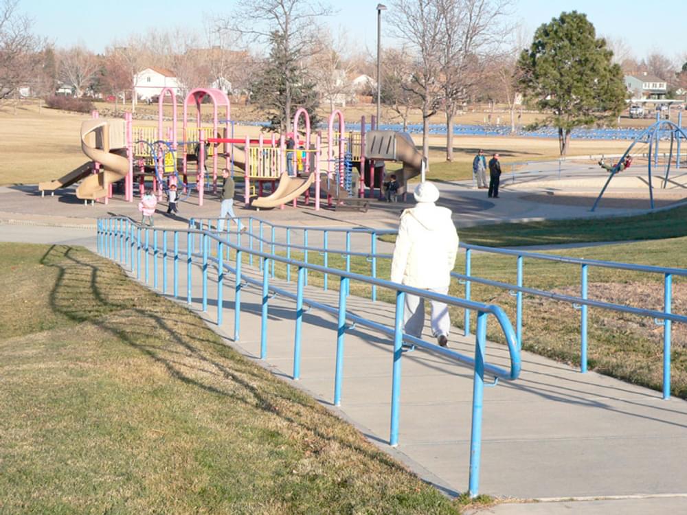 Ramp used in a park with handrails following building standard rather than more appropriate Accessible Recreation Route guidelines which would omit railings; Aurora, Colorado