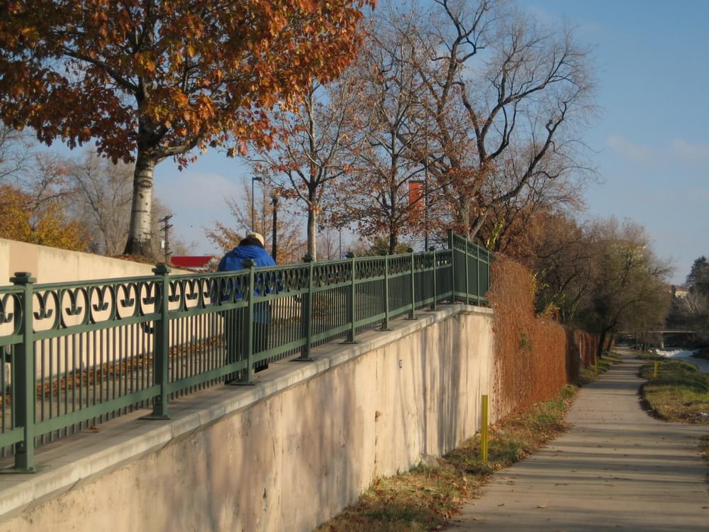 Engineered ramp along vertical wall brings pedestrians and bikers from sidewalk along Speer Blvd down to Cherry Creek Trail, Denver