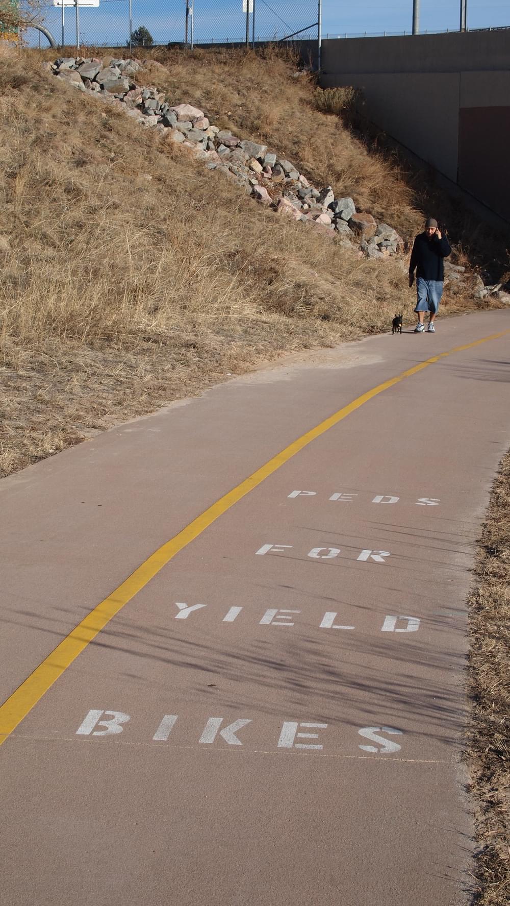 Stencils on trail pavement reinforce yield message on Cherry Creek Trail in Denver, Colorado