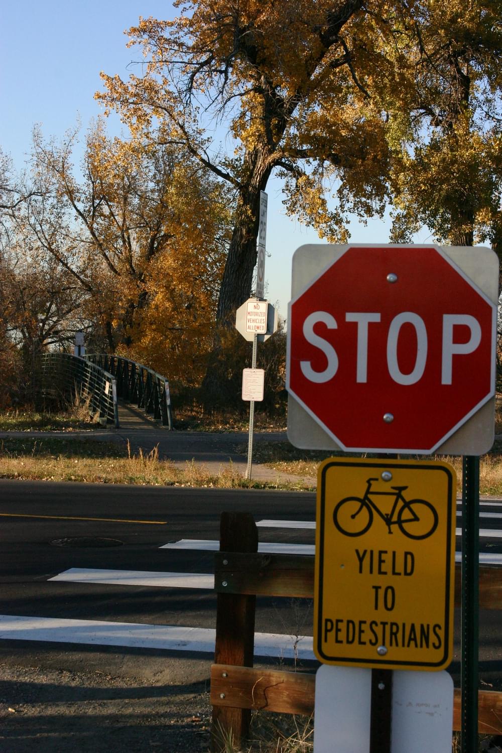 Bicycles yield to pedestrian sign at road crossing, Highline Canal Trail through Bible Park; Denver, Colorado