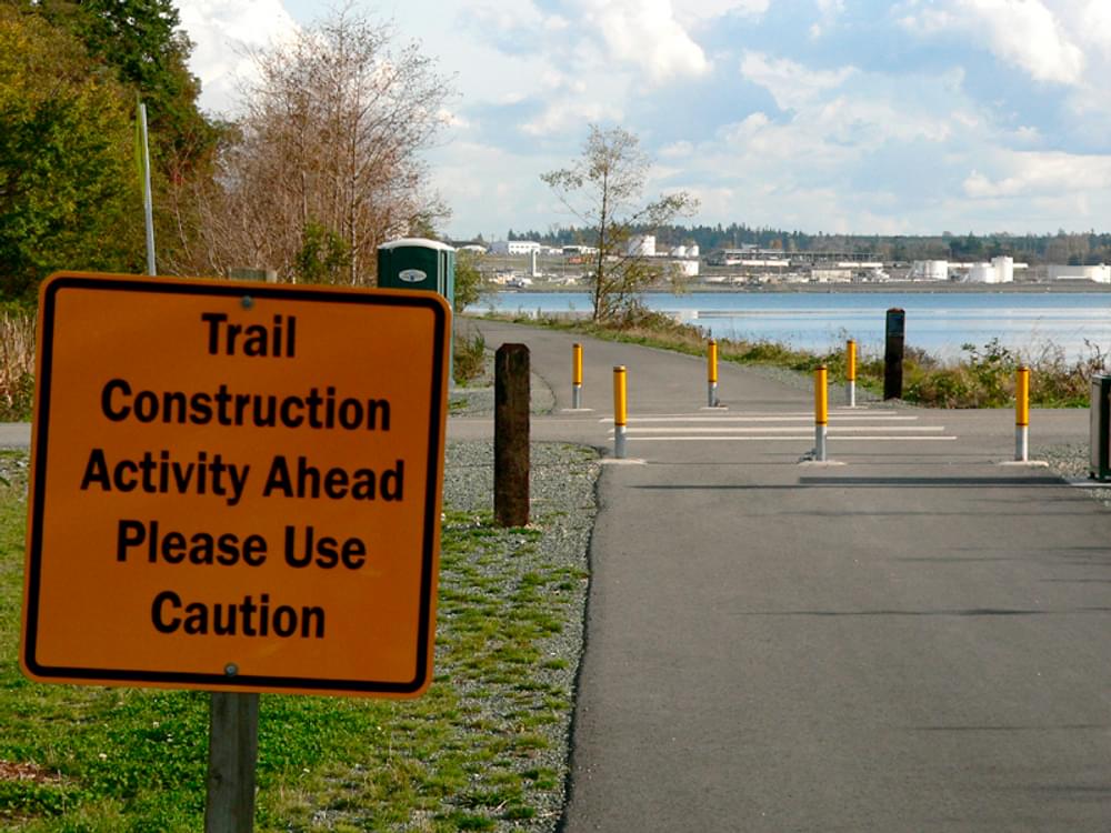Sign warning of construction activity ahead on rail trail in Anacortes, Washington