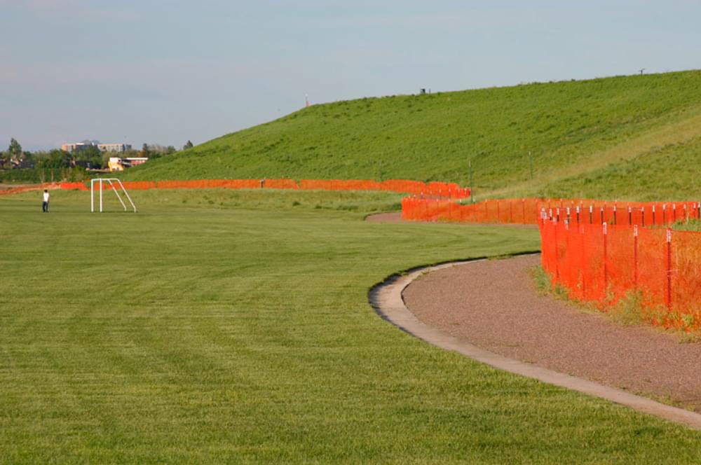 Orange plastic safety fencing used to keep trail users from climbing face of Westerly Creek Dam, Denver