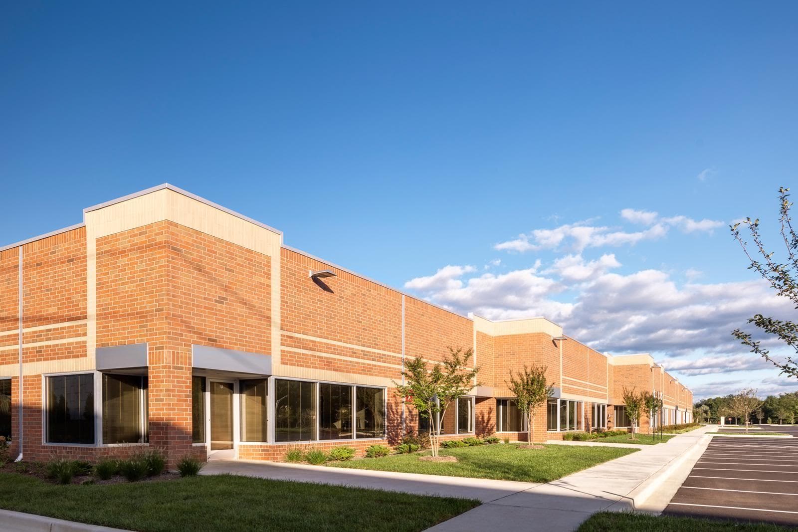 An alternate view of 5600 – 5751 Rivertech Court. The corner of a brick building with Walking paths all around the building with convenient parking out front