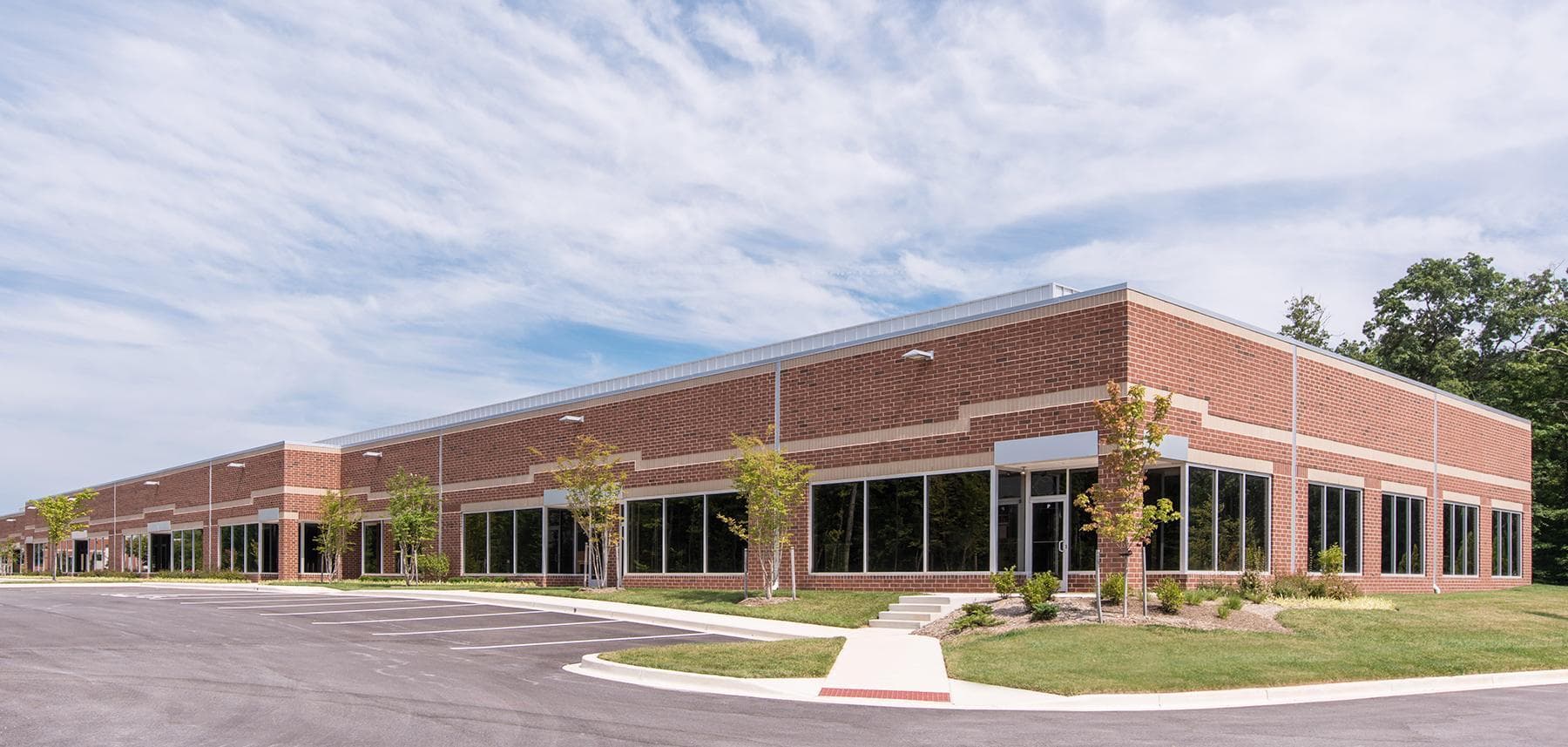 Corner of a brick building with modern white framed windows along the side, and walking paths all around at 5600 – 5751 Rivertech Court