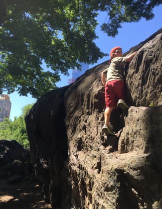 A boy climbs on the rocks along the trail in Central Park. Photo by Chris Sheffield.