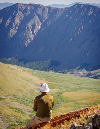 A volunteer with Volunteers for Outdoor Colorado and Colorado Fourteeners Initiative takes a break from trail work to enjoy the view, looking down the Grays Peak trail.