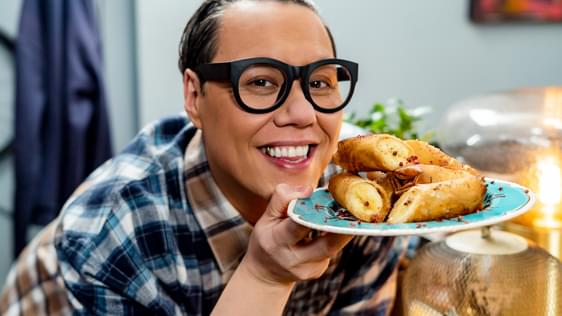 Gok Wan holding a plate of food and smiling.