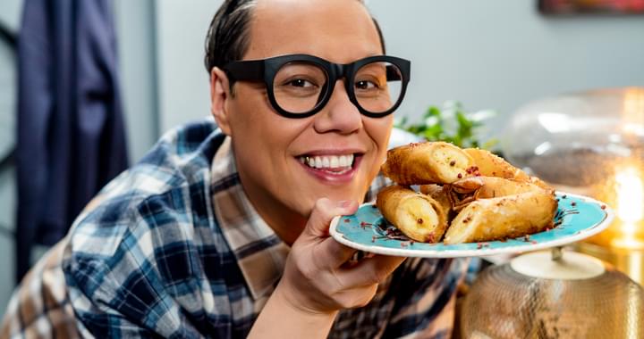 Gok Wan holding a plate of food and smiling.