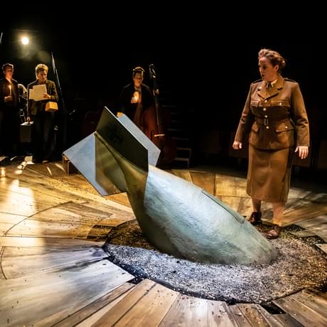 World War 2 bomb in centre of stage with women looking at it