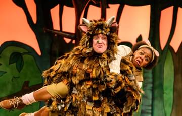 A man dressed as Gruffalo carrying a woman dressed as a mouse