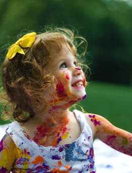 Child covered in paint having fun